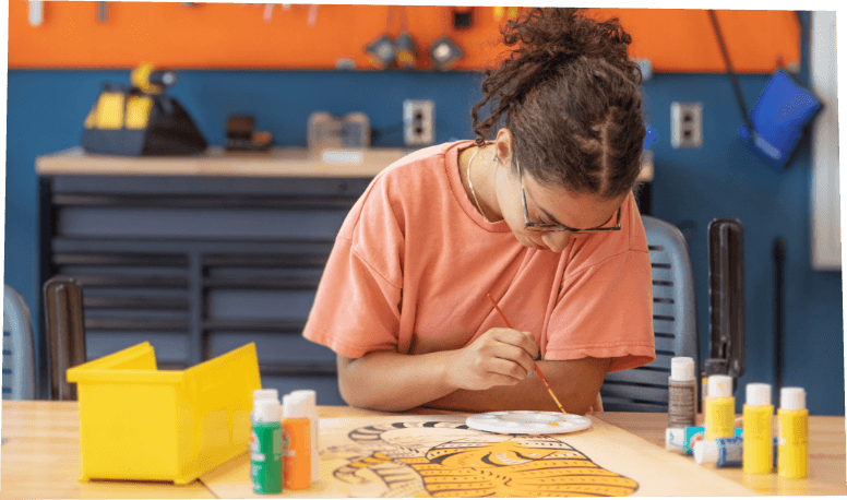 Student painting at a table with creative tools